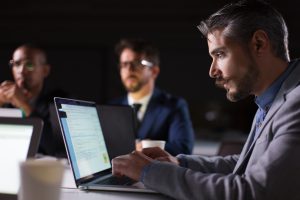 Focused bearded office employee looking at laptop