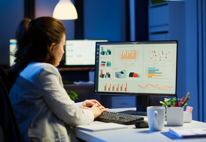 Busy woman working at night in front of computer taking notes