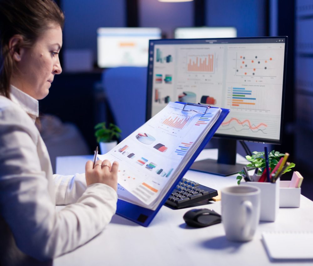 FreelanACcer woman comparing graphics from clipboard with grafics from computer