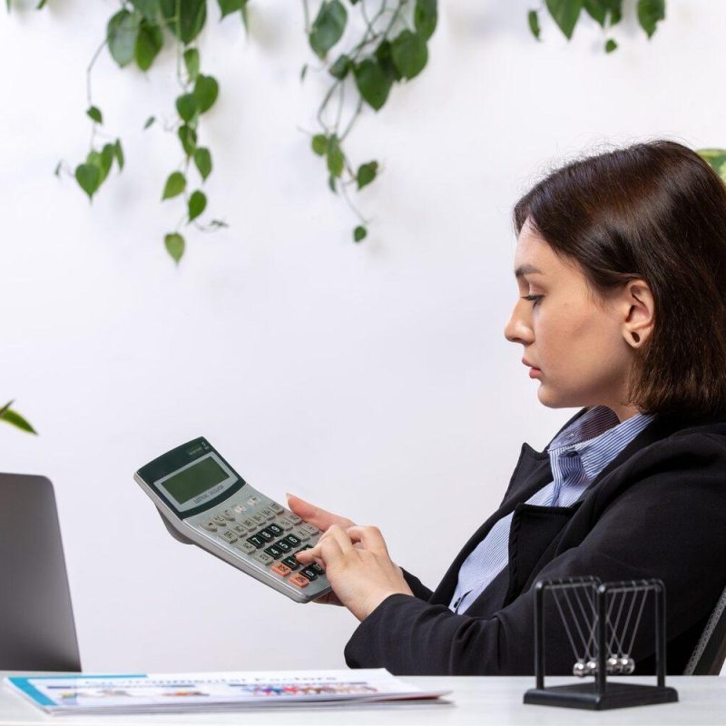 front-view-beautiful-young-businesswoman-black-jacket-blue-shirt-working-with-calculator-front-table-business-job-office
